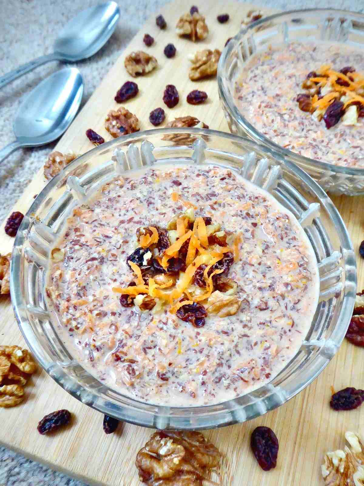 zoomed in on one flaxseed pudding in a glass bowl with 2 spoons and other serving bowl in the background