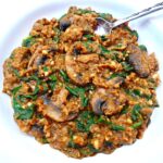 pumpkin and mushroom risotto with spinach served in a bowl with a spoon